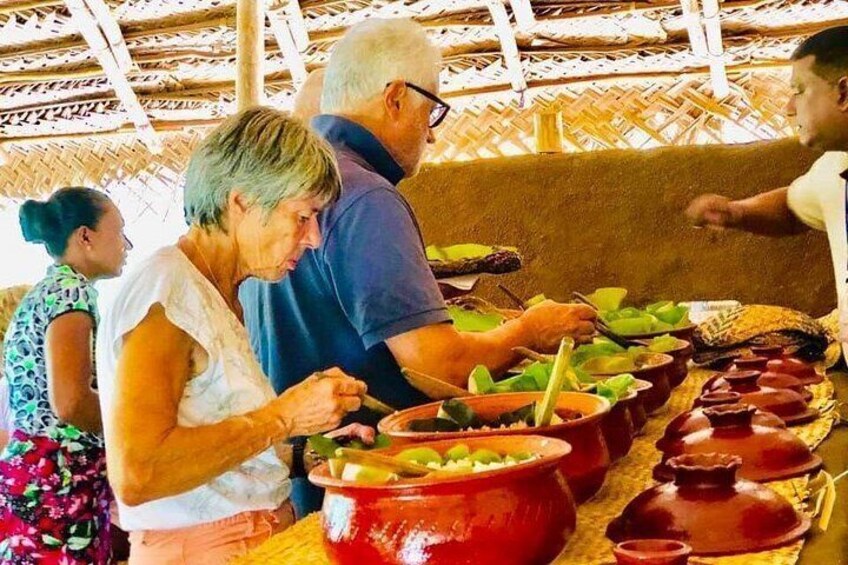 People serving food at a communal meal with large pots and bowls. 5