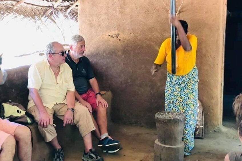 A person standing on a stool, holding a pole, with two seated men in the background. 4