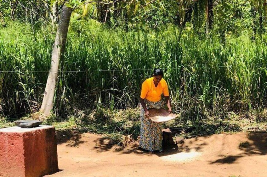 A person in a yellow shirt and patterned skirt working with a large basket in a field. 3