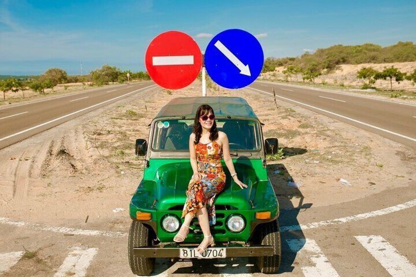 A woman in a floral dress sitting on a green vehicle with a 'no entry' and 'right turn only' sign above it. 2