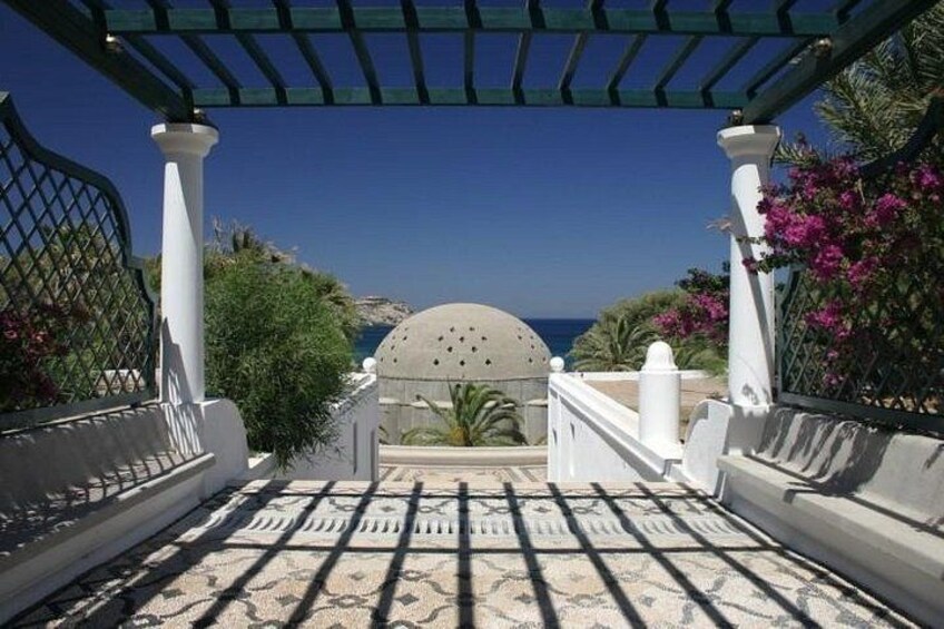 Eine weiße Pergola mit einem gemusterten Boden, der zum Blick auf das Meer führt. 5
