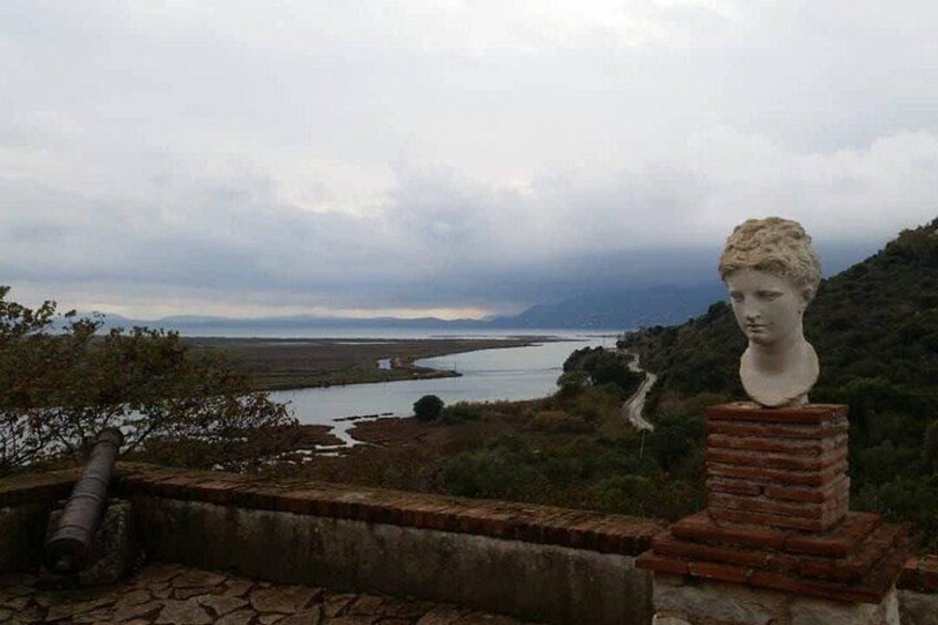 A landscape with a bust on a brick pedestal, a cannon, and a winding path leading to a body of water. 5