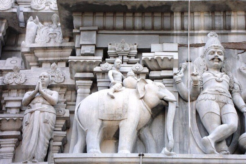 A stone sculpture of a deity with an elephant, a seated figure, and a standing figure. 5