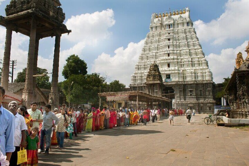 A temple with a large, tiered gopuram, a crowd of people, and a clear sky. 5