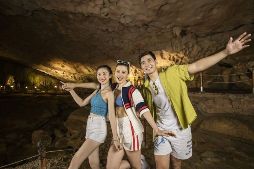 Three people in a cave with rocky walls and a railing. 3