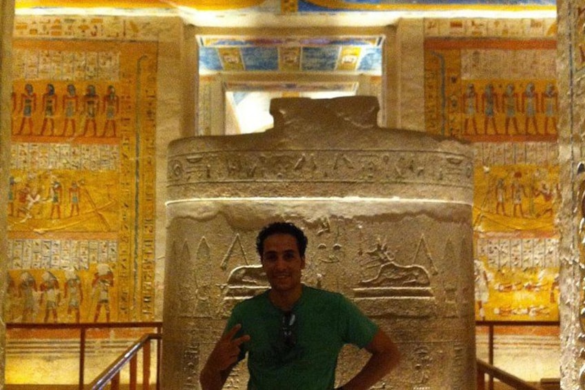 A person standing in front of an ancient Egyptian sarcophagus with hieroglyphics. 5