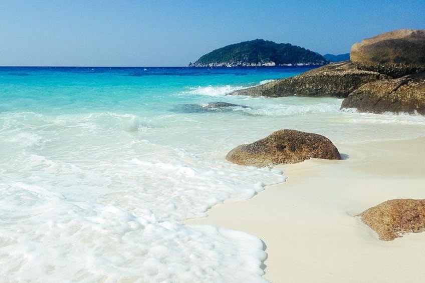 Una playa con aguas turquesas cristalinas, arena blanca y rocas grandes. 5