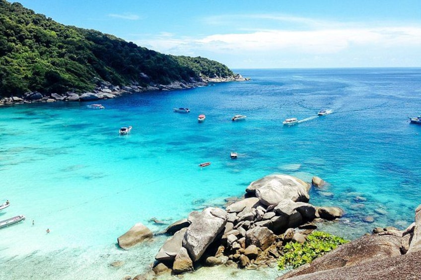 Un paisaje costero con aguas turquesas cristalinas, afloramientos rocosos y barcos. 3