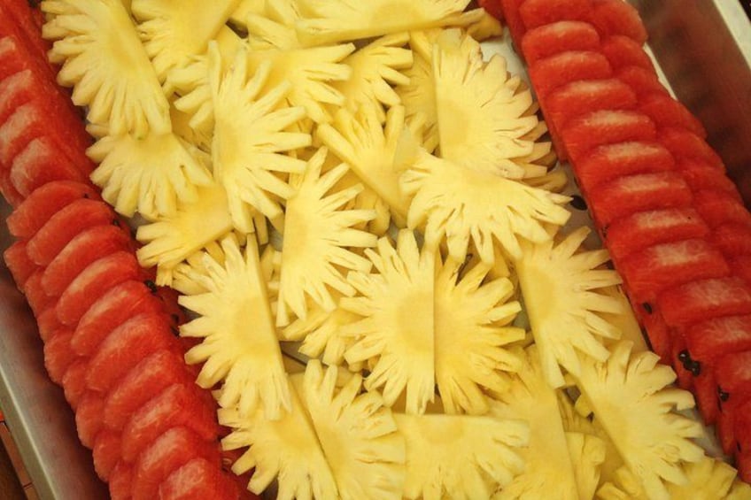 Presentación de frutas cortadas, como piña y sandía, dispuestas en una bandeja. 4