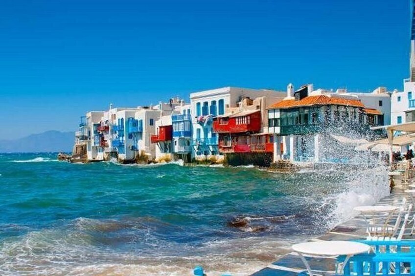 Un borgo costiero con edifici colorati, un mare blu cristallino e una barca in primo piano. 1