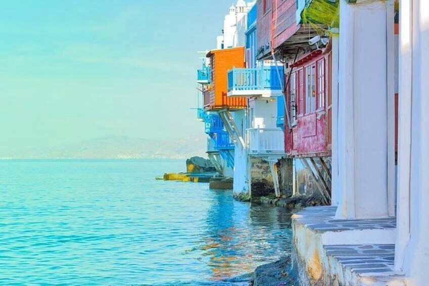 Una riva con edifici colorati, acqua calma e cielo sereno. 5