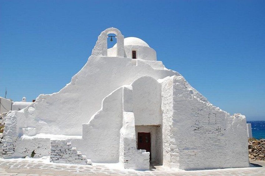 Un edificio bianco a cupola, con un campanile e un portale, sullo sfondo di un cielo azzurro intenso. 4