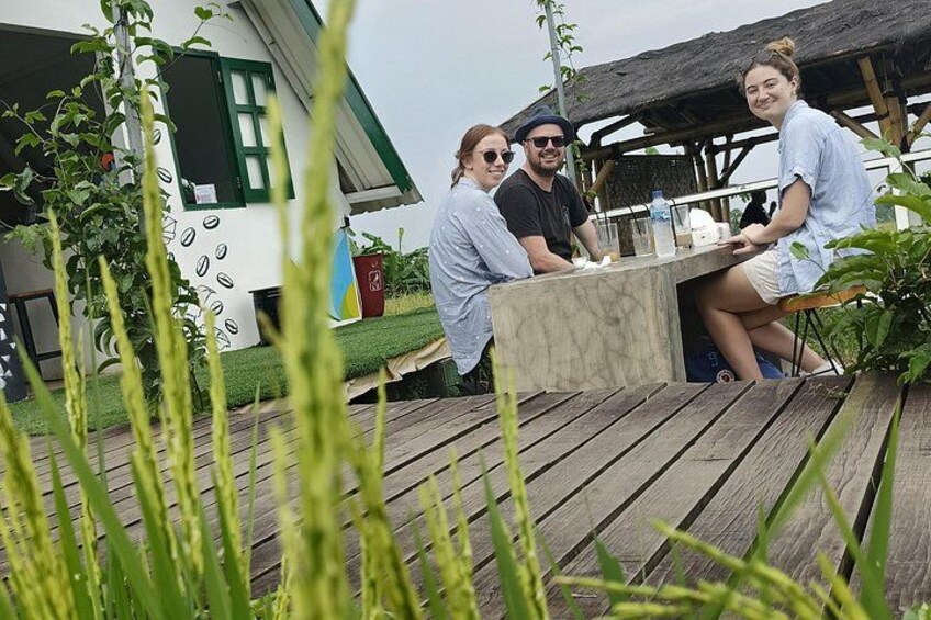 En grupp människor sitter vid ett utomhusbord med ett hus i bakgrunden. 5