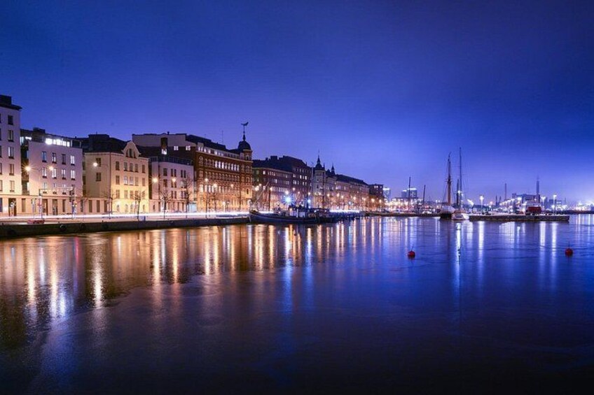 A waterfront cityscape at night with illuminated buildings and boats. 1