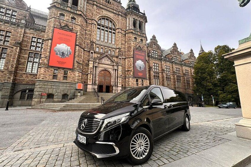 A black Mercedes-Benz SUV parked in front of a historic building with large banners. 1