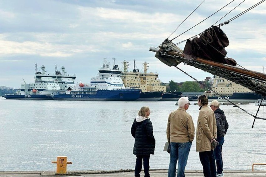 A group of people standing by a dock, looking at a large ship named 'Polaris' with another ship in the background. 1