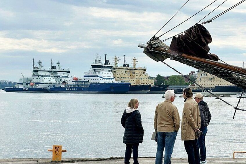 Un groupe de personnes se tient près d’un quai, regardant un grand navire nommé « Polaris » qui se trouve au loin. 2