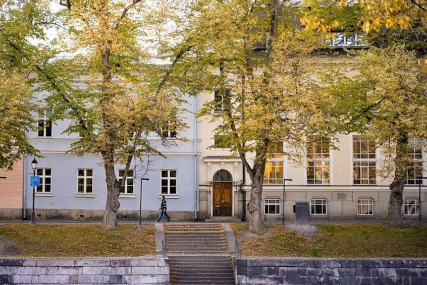 A building with a staircase leading up to an arched entrance, surrounded by trees with autumn leaves. 5