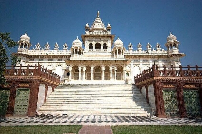A grand white building with multiple domes and arches, a large staircase leading to the entrance, and a checkered pathway in front. 3