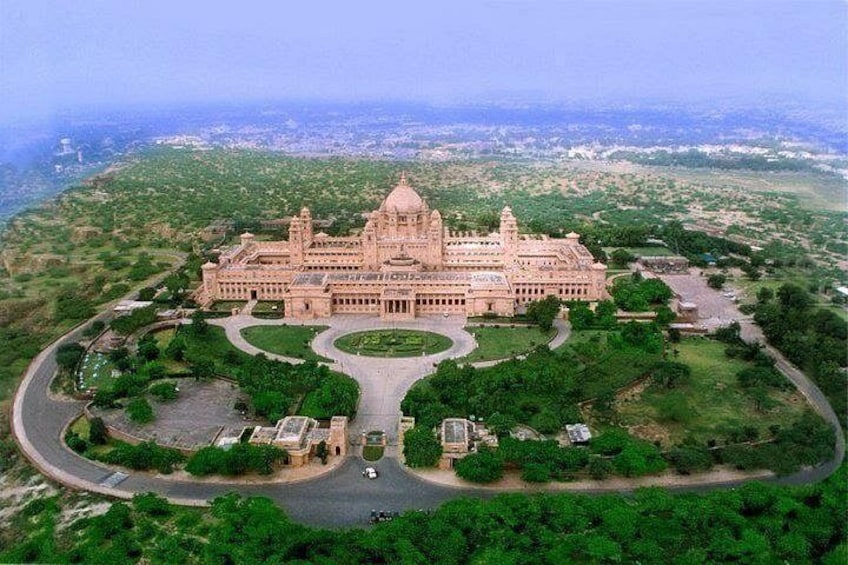 A large, ornate building with a central dome, surrounded by lush greenery and a winding road. 5