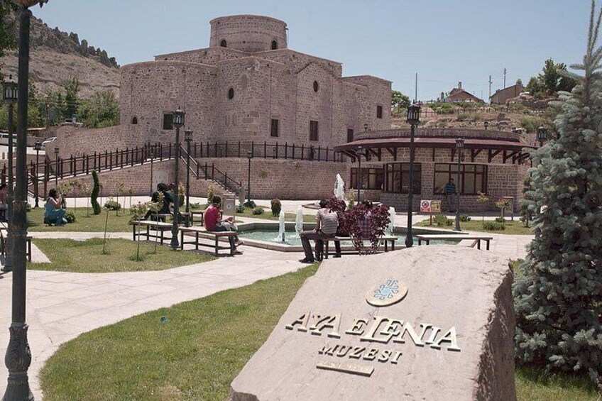 A historic building with a circular tower, a paved pathway, and a plaque with text. 4