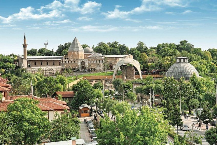 A historic building with domes and arches, surrounded by lush greenery and trees. 1