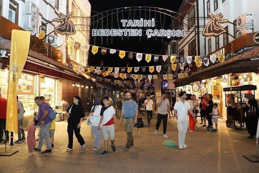 A crowded street with people walking, shops, and a sign reading 'TARİHİ BEDESTEN CARSİSİ'. 5