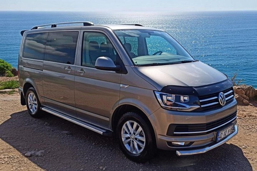 A silver Volkswagen van parked on a coastal road with the ocean in the background. 2