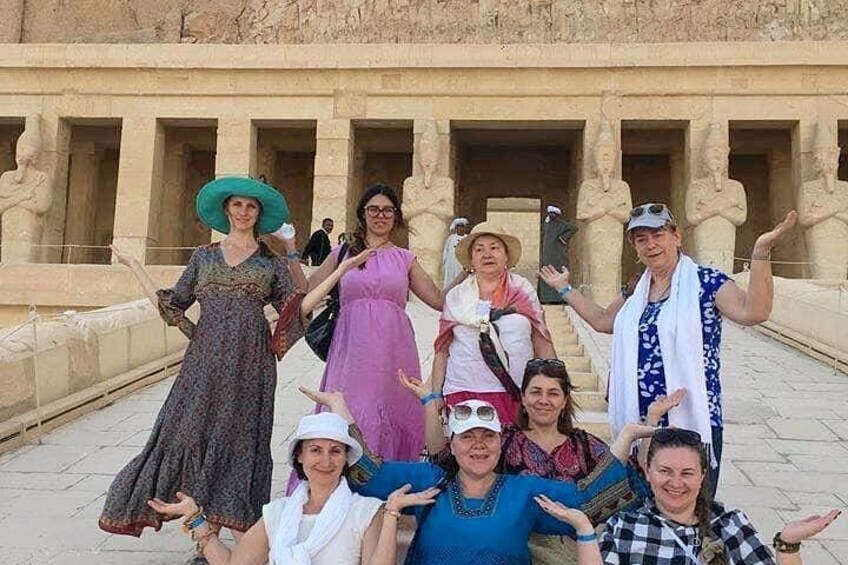 A group of people posing in front of an ancient Egyptian temple with columns and hieroglyphs. 3
