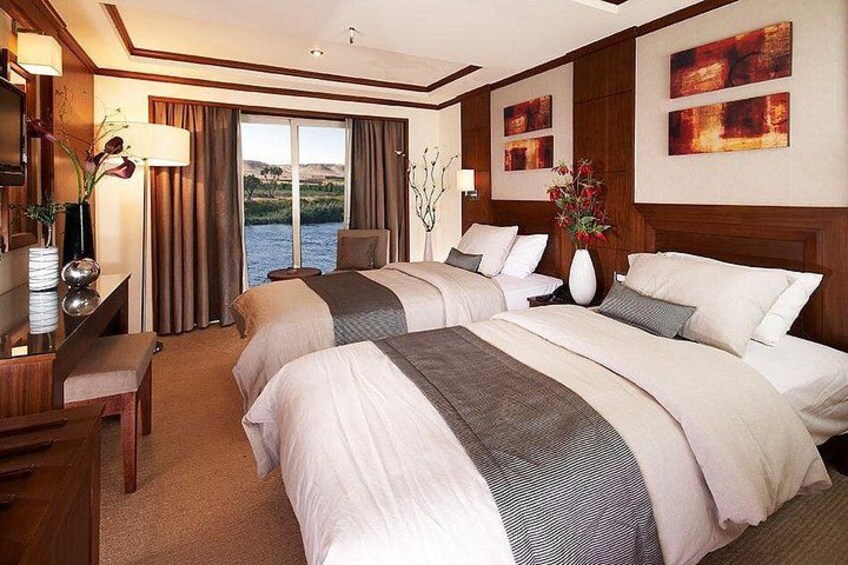 A hotel room with two beds, a desk, and a view of a body of water. 4
