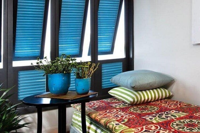 A room with a bed, a small table with potted plants, and a window with blue blinds. 4