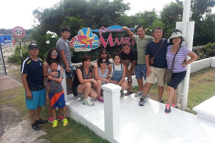 A group of people posing in front of a 'Welcome to St. Maart' sign. 4