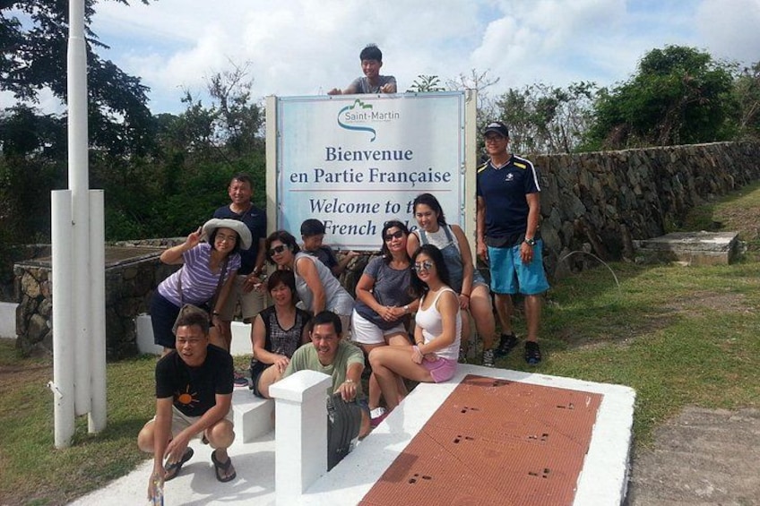 A group of people posing in front of a welcome sign at Saint-Martin. 5