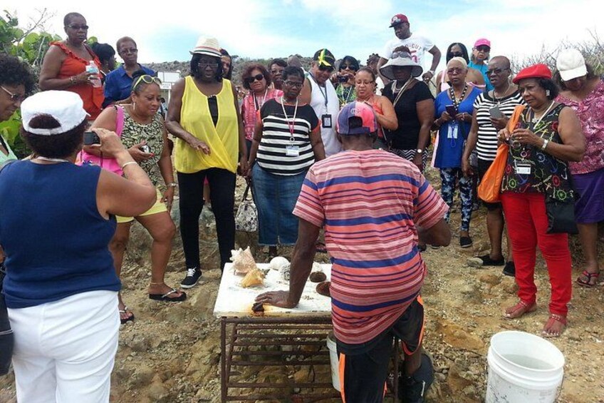 A group of people gathered around a table with food items, possibly at an outdoor event or market. 3