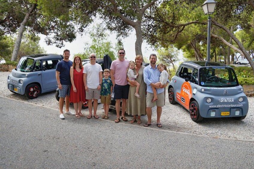 A group of people posing with electric cars on a paved road. 3