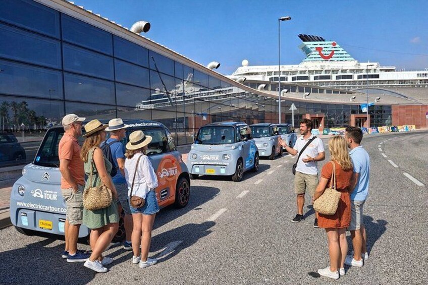 A group of people standing in a parking lot with a cruise ship in the background. 4