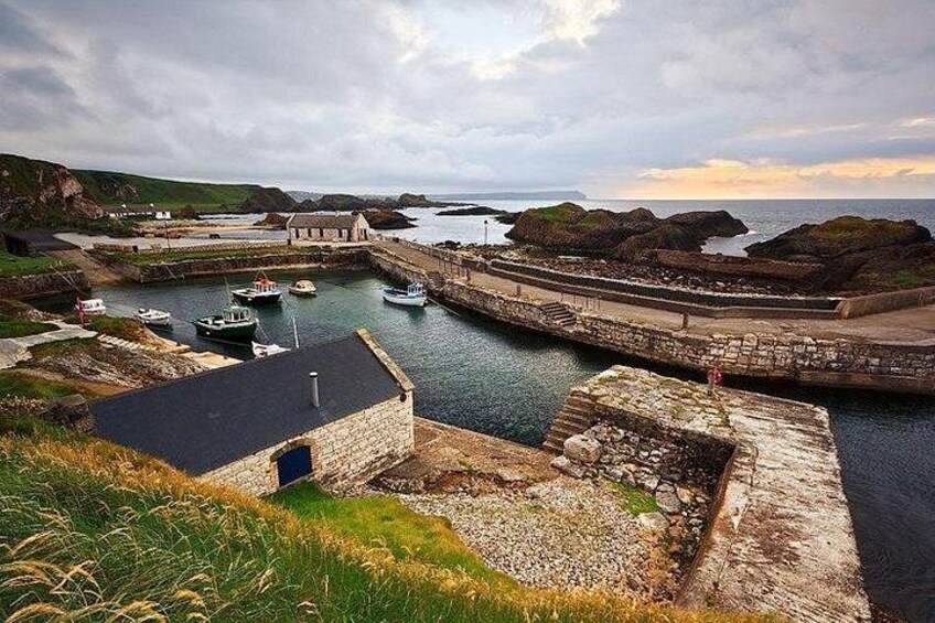A coastal harbor with boats, a stone building, and rocky outcrops. 3