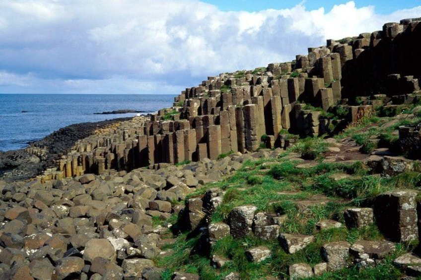A coastal landscape with ancient stone structures and a rocky shoreline. 2