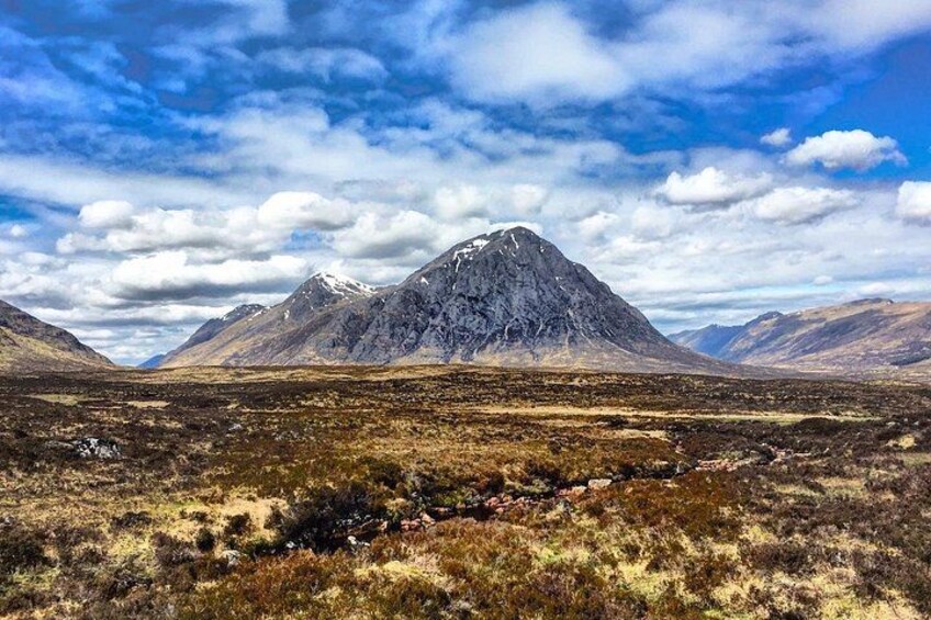 A mountainous landscape with a prominent peak, a valley, and a clear sky. 2