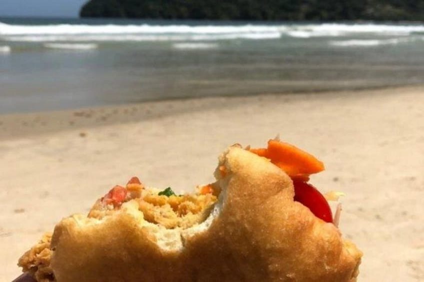 A close-up of a food item on a beach with the ocean and a distant island in the background. 1