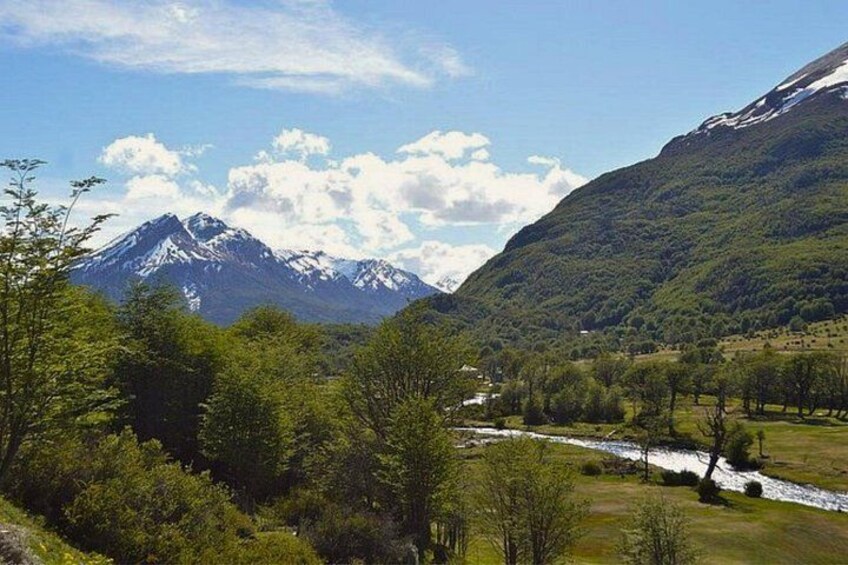 A mountainous landscape with a river, trees, and a clear sky. 4