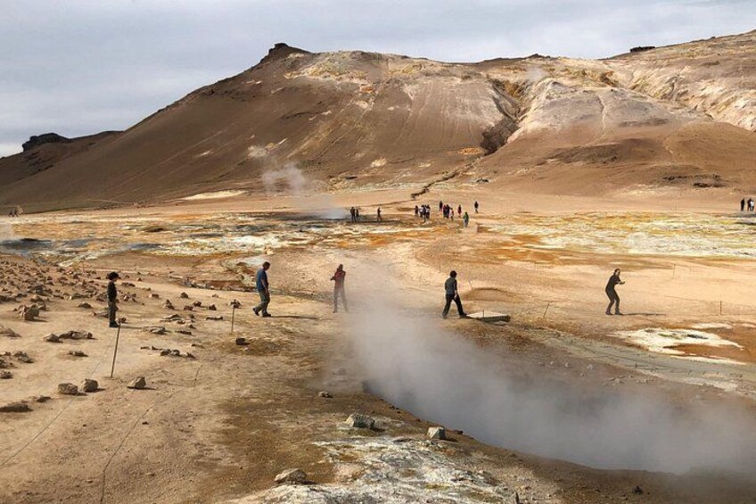 A geothermal area with steam vents and people walking around. 2