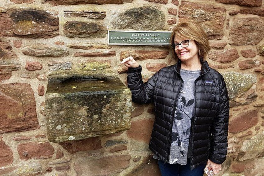 A stone wall with a plaque and a stone well. 3