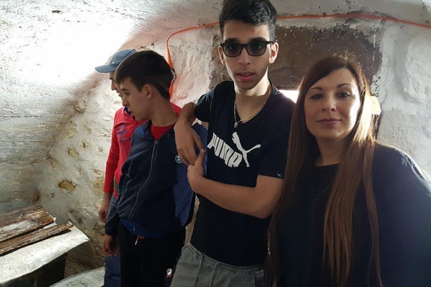 A group of people in a cave-like structure with rough walls and a wooden bench. 3