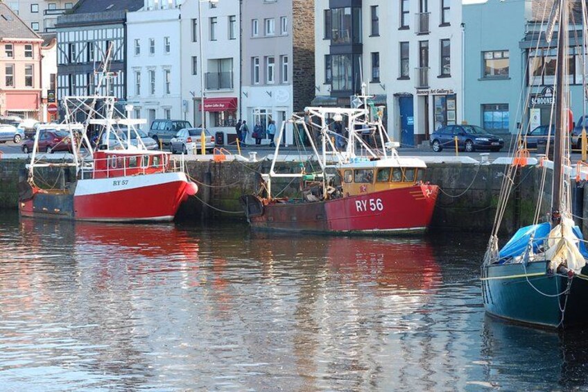A harbor with several boats docked, including a red and white boat with the number 'RY 57' and a red boat with the number 'RY 56'. 1