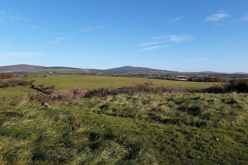 A grassy field with a stone wall and distant hills. 3