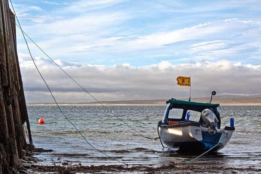 A small boat with a yellow flag, anchored near a wooden structure by the water. 5