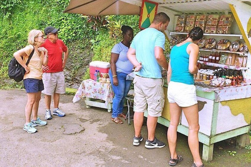 A group of people at a roadside stall with a table and various items on display. 3