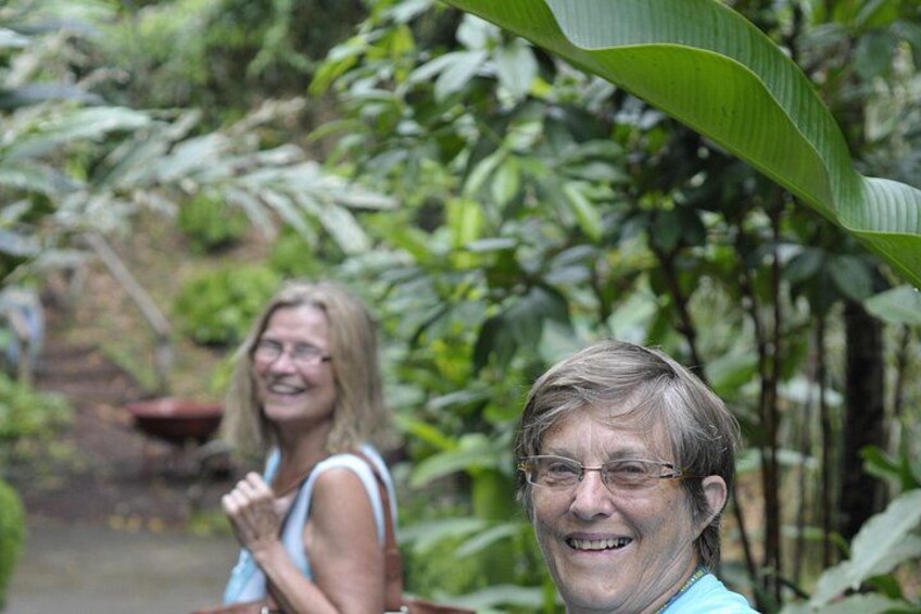 Two people in a lush green garden with dense foliage and a banana plant. 3
