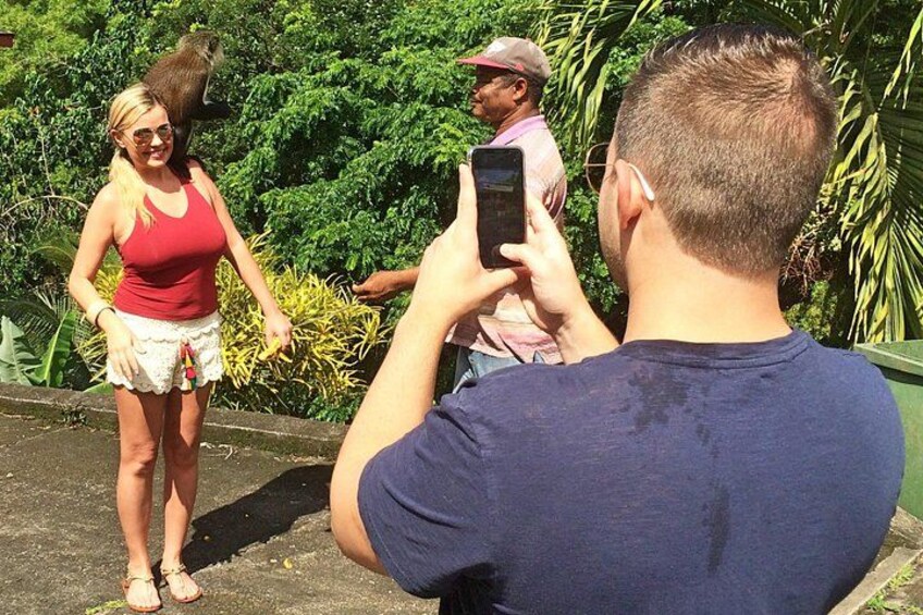 A person taking a photo of another person standing outdoors with greenery in the background. 4